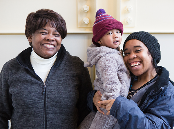 Two smiling women and a toddler standing together