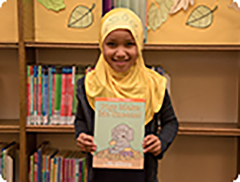 Smiling young girl holding Somali alphabet book