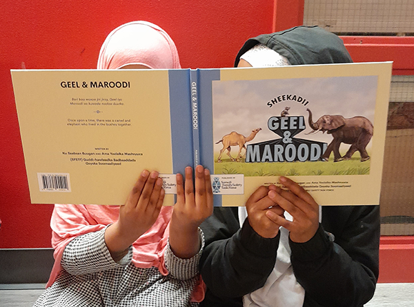 Image of two children holding a book titled "Geel & Marood"