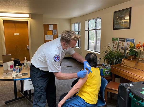Member of Seattle Fire Department gives a person a vaccine 
