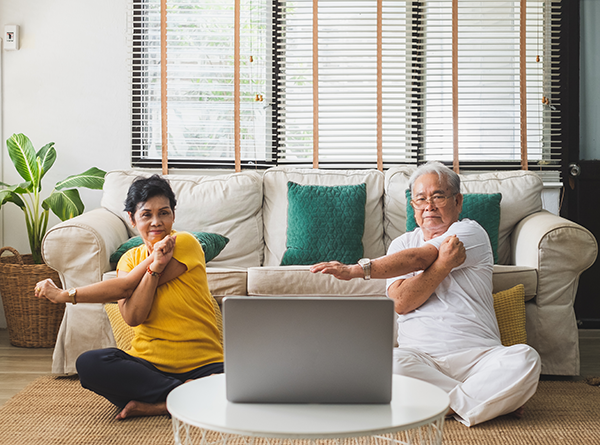 Two elderly people exercising at home