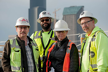 Group of four people standing wearing hard hats