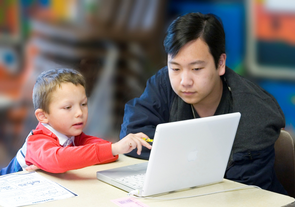 Child and adult looking at laptop computer