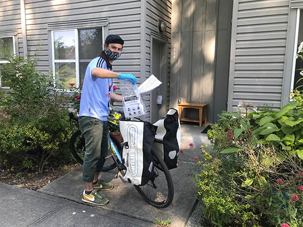 Young man delivering masks by bicycle