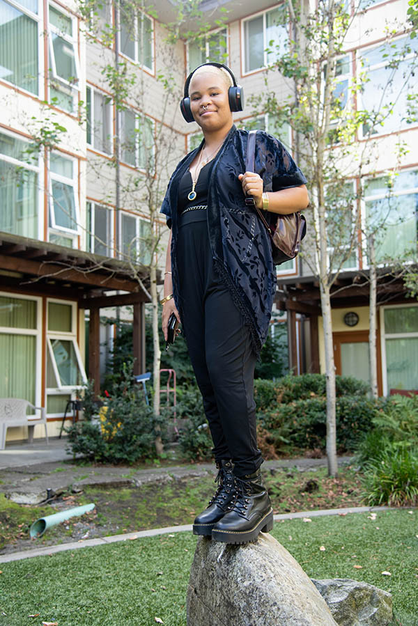 Young woman wearing headphones standing on a rock