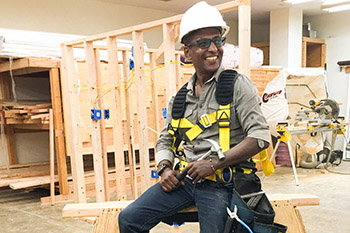 Man in construction gear sitting on a saw horse at building site