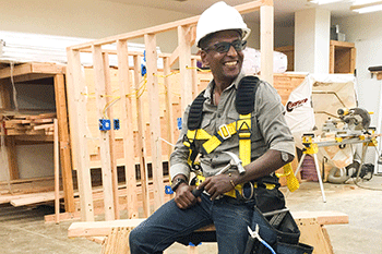 Man in construction gear seated on a saw horse