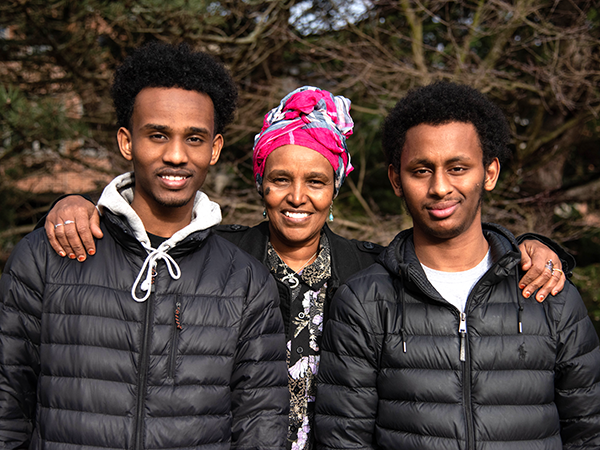 Woman standing with two teenage boy high school graduates