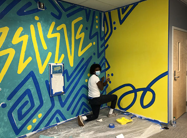 Young man painting a mural on a wall