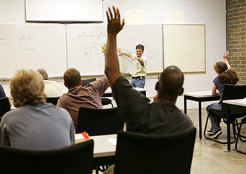 man raises hand in adult education classroom