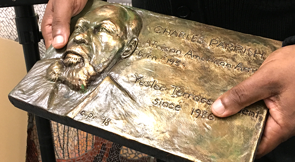 Hands holding bronze plaque with engraving and molded portrait