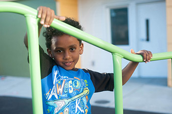 Smiling small boy holding on to railing