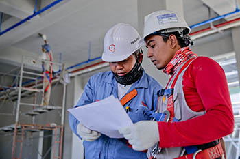 Two people in hard hats reading a paper