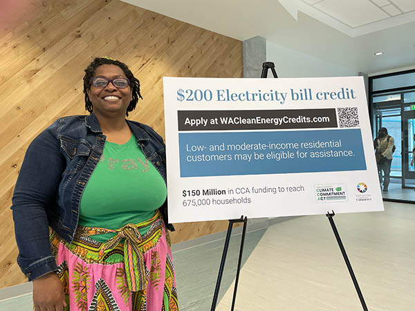 woman stands in front of sign about Clean Energy Credit