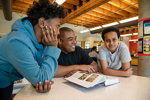 Two boys and and adult man sit at a table