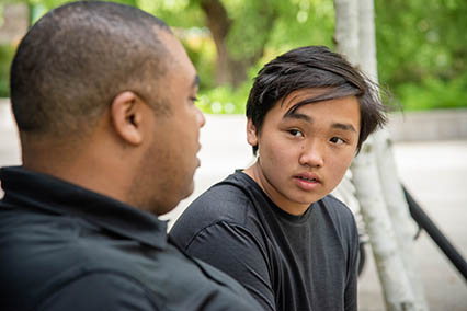 Man and boy talk while sitting on bench