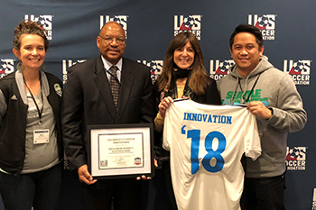 Four people standing and holding up award certificate