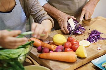 two people cutting vegetables