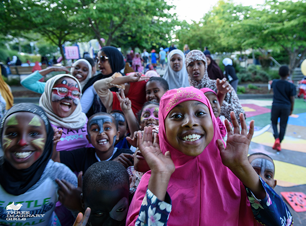 Group of smiling teens and kids, many with their faces painted, walking outdoors