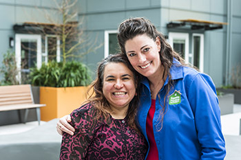 Two smiling women stand together in courtyard of apartment building