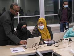 Three people looking at a computer
