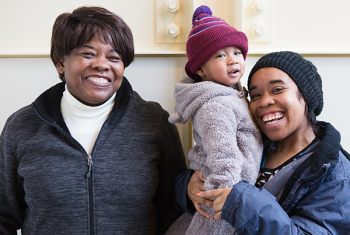 Two smiling women and a toddler standing together