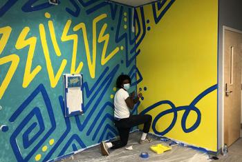 Young man painting a mural on a wall