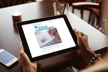 Woman's hands holding iPad with The Voice newsletter displayed on it