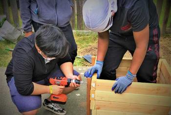 Man and teen boys build raised garden bed for NewHolly youth garden