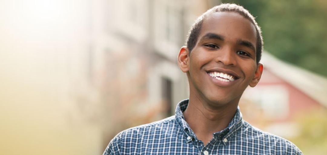 Smiling young man stands in front of buildings 