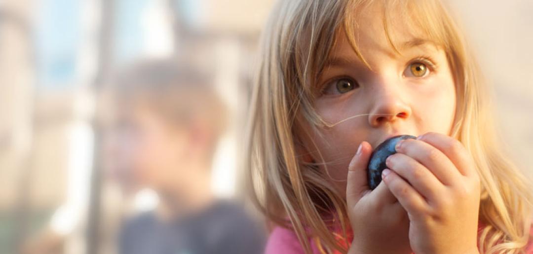 Young girl eating a plum