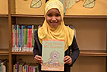Smiling young girl holding Somali alphabet book