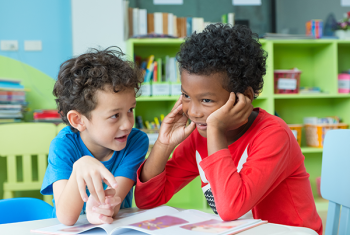 Two small boys seated around table and talking