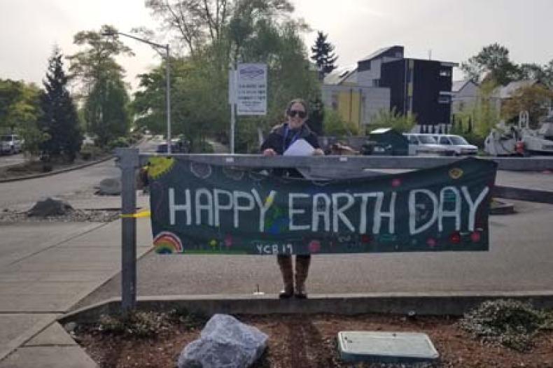 Woman standing near "Happy Earth Day" banner