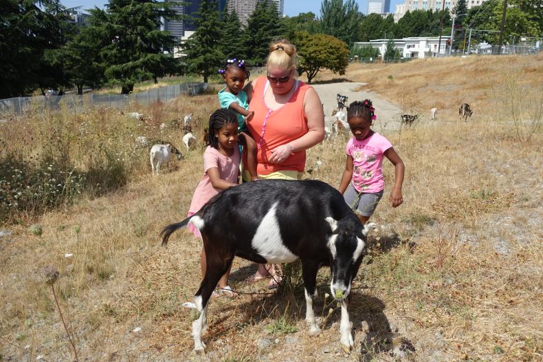 A woman and three children near a goat