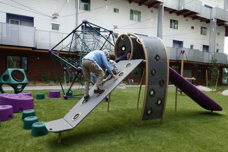 Woman and small boy climb slide in play area