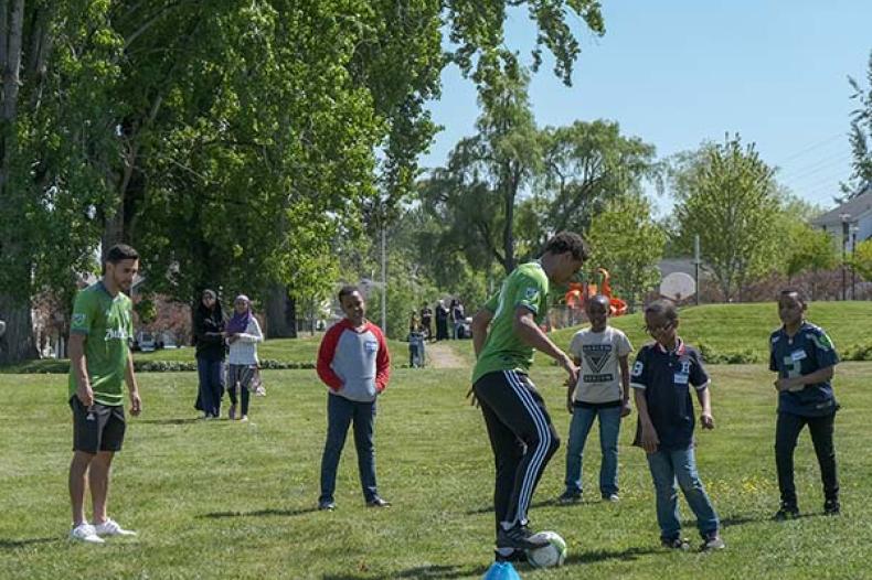 Adult soccer player demonstrates for kids standing and listening on field