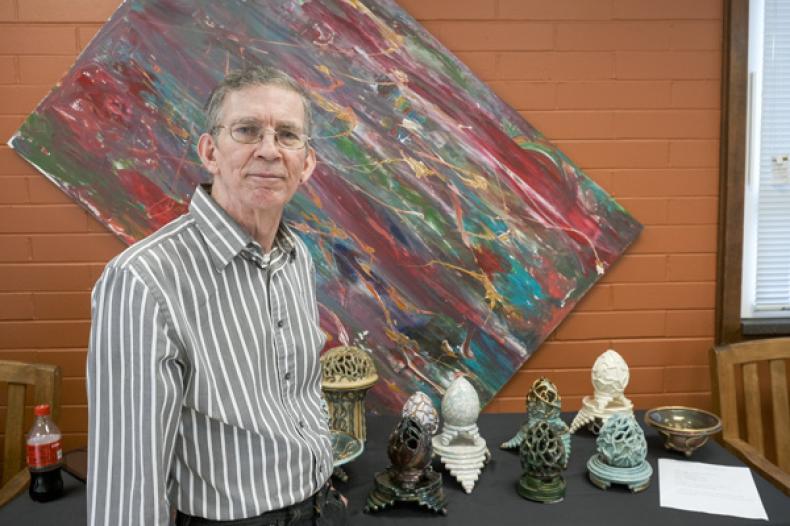 Man standing in front of painting and sculptures