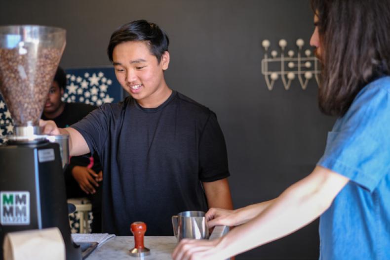 Teenage boy brews coffee on espesso machine