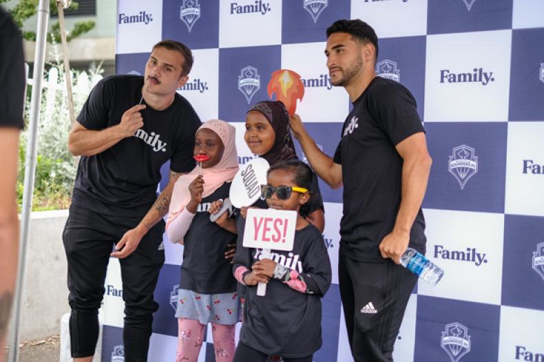 Sounders players and kids at RAVE Foundation 'Family' celebration at Yesler Terrace Park's RAVE soccer field
