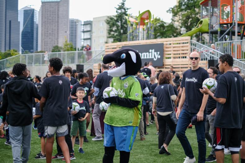 Sammy the Sounder mascot stands with others in Yesler Terrace park's Rave field for Rave Foundation event