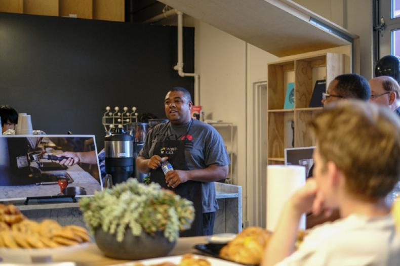 Young man explains coffee program to visiting group