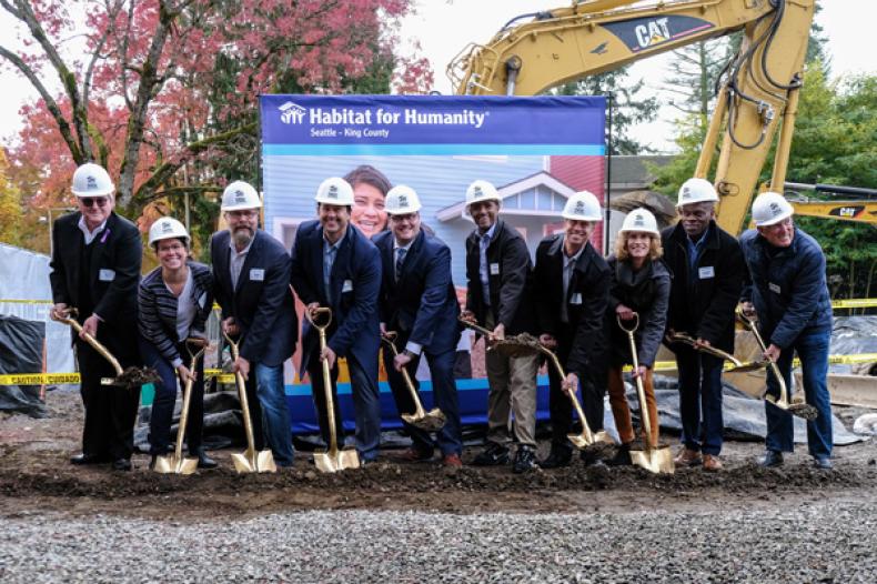 Officials with shovels break ground with "Habitat for Humanity" banner in background
