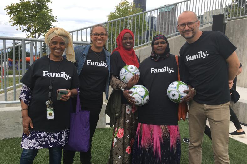 Smiling group of adults standing and holding soccer balls