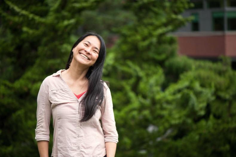 Woman standing with greenery in the background