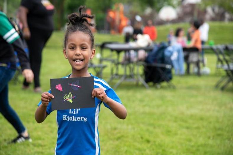 Image of young girl holding her drawing
