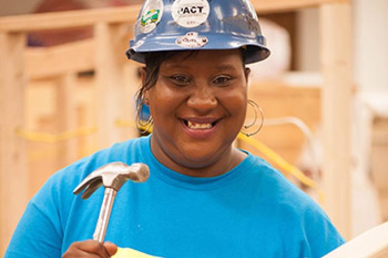 Woman in hard hat holding hammer and board
