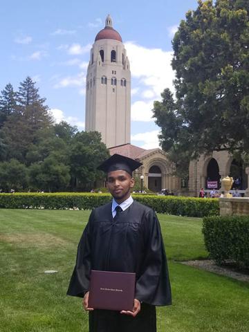 Young man in cap and gown on a campus