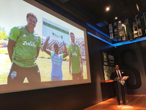 Man at podium surrounded by Sounder soccer paraphernalia