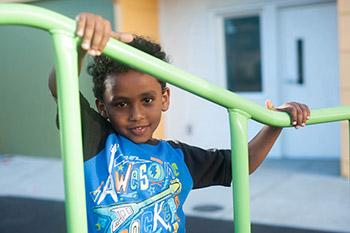 Smiling small boy holding on to railing